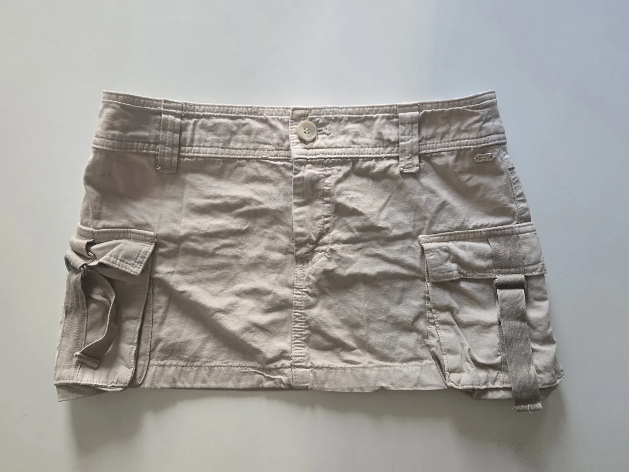 Pollera cargo de gabardina color beige. Posee bolsillos. 
(tiene dos pequeñas manchas en la parte de atras)