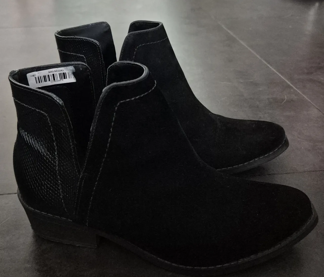 Botitas negras de gamuza con recortes laterales y detalle de textura tipo serpiente. Un calzado súper versátil para elevar cualquier look.