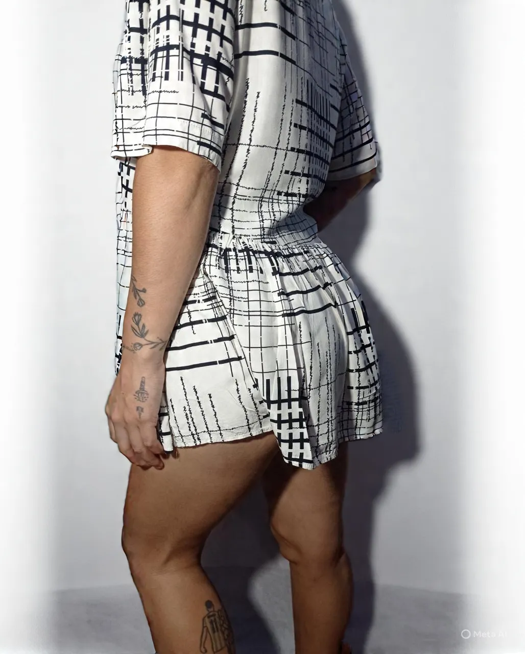 Vestido corto blanco con estampa de líneas negras. Posee cuello en V y botones al frente. Tiene mangas cortas y elástico en la cintura con volado en la parte inferior.