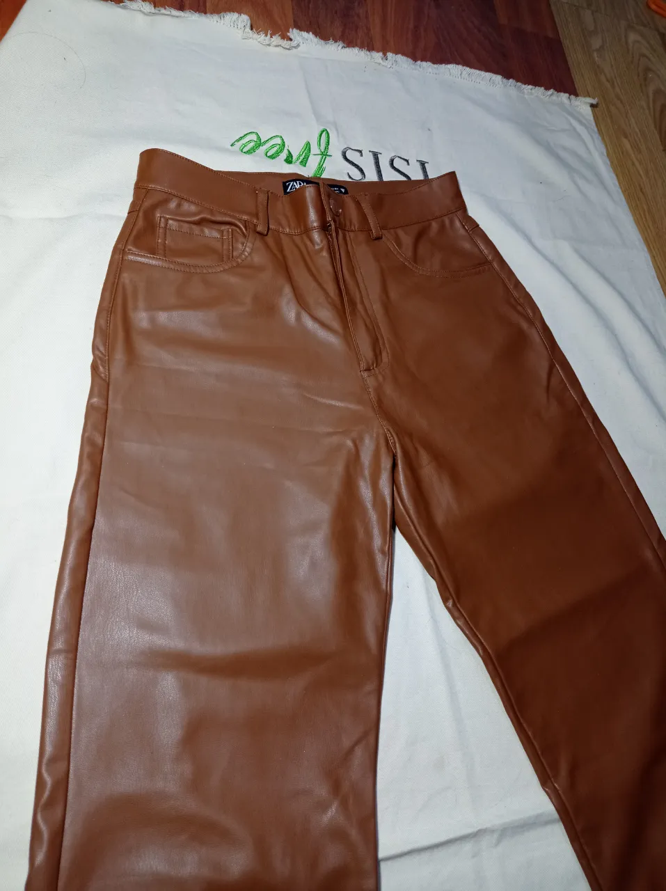 Pantalón de cuero sintético color marrón. Posee bolsillos delanteros y traseros.