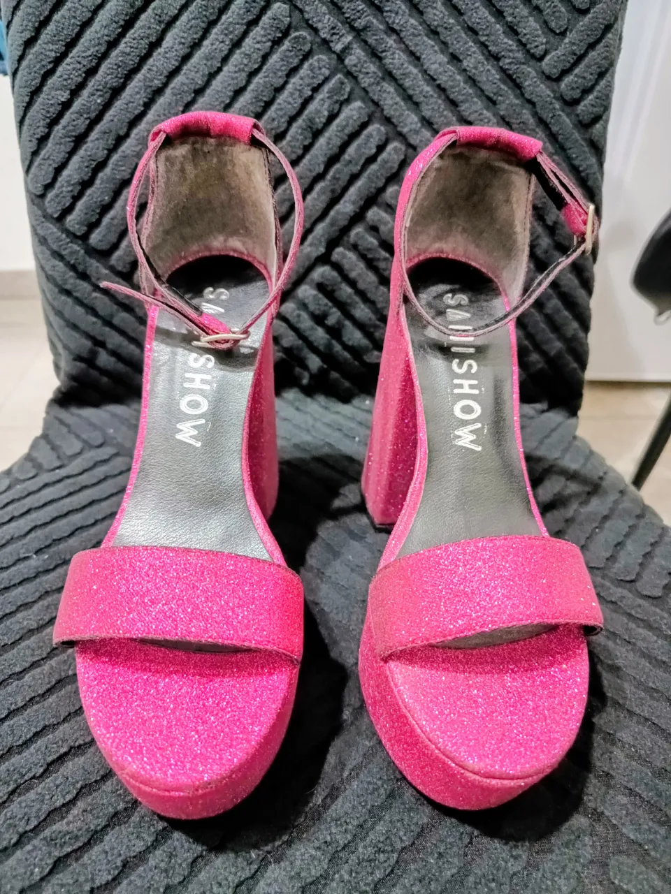 Sandalias con brillos color fucsia. Tienen una tira ancha en la parte delantera y una tira fina con hebilla en el tobillo. Taco grueso y plataforma.