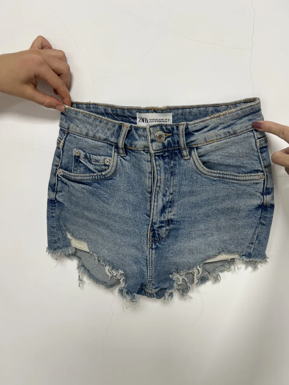 Short de jean Zara tiro alto con roturas y detalles desflecados en los bordes.