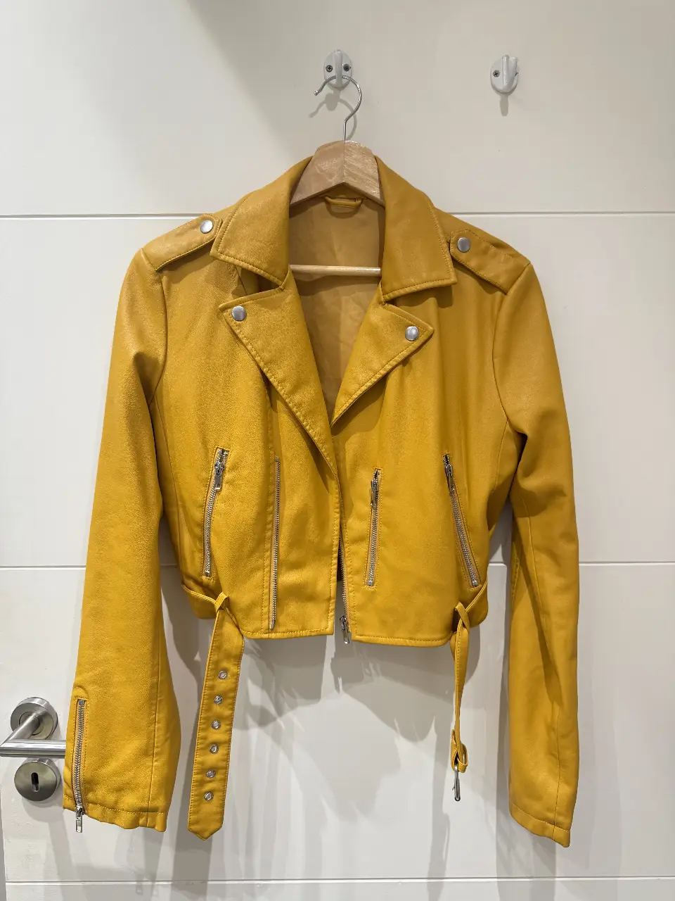 Campera corta de cuerina color mostaza, con cierre y detalles metálicos. Ideal para un look moderno y canchero. Con pequeño detalle en una manga.