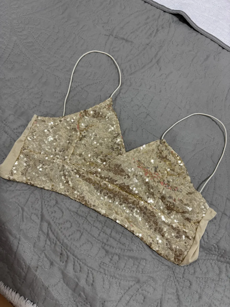 Top corto con lentejuelas doradas y detalle de nudo en la parte trasera. Breteles finos.