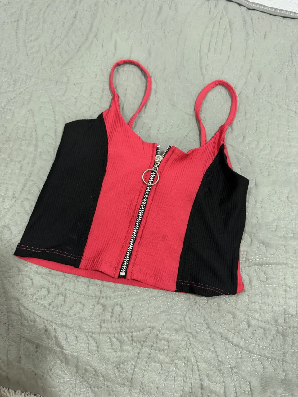 Top corto de breteles finos con cierre metálico al frente y detalle de aro. Diseño combinado en color rojo y negro.