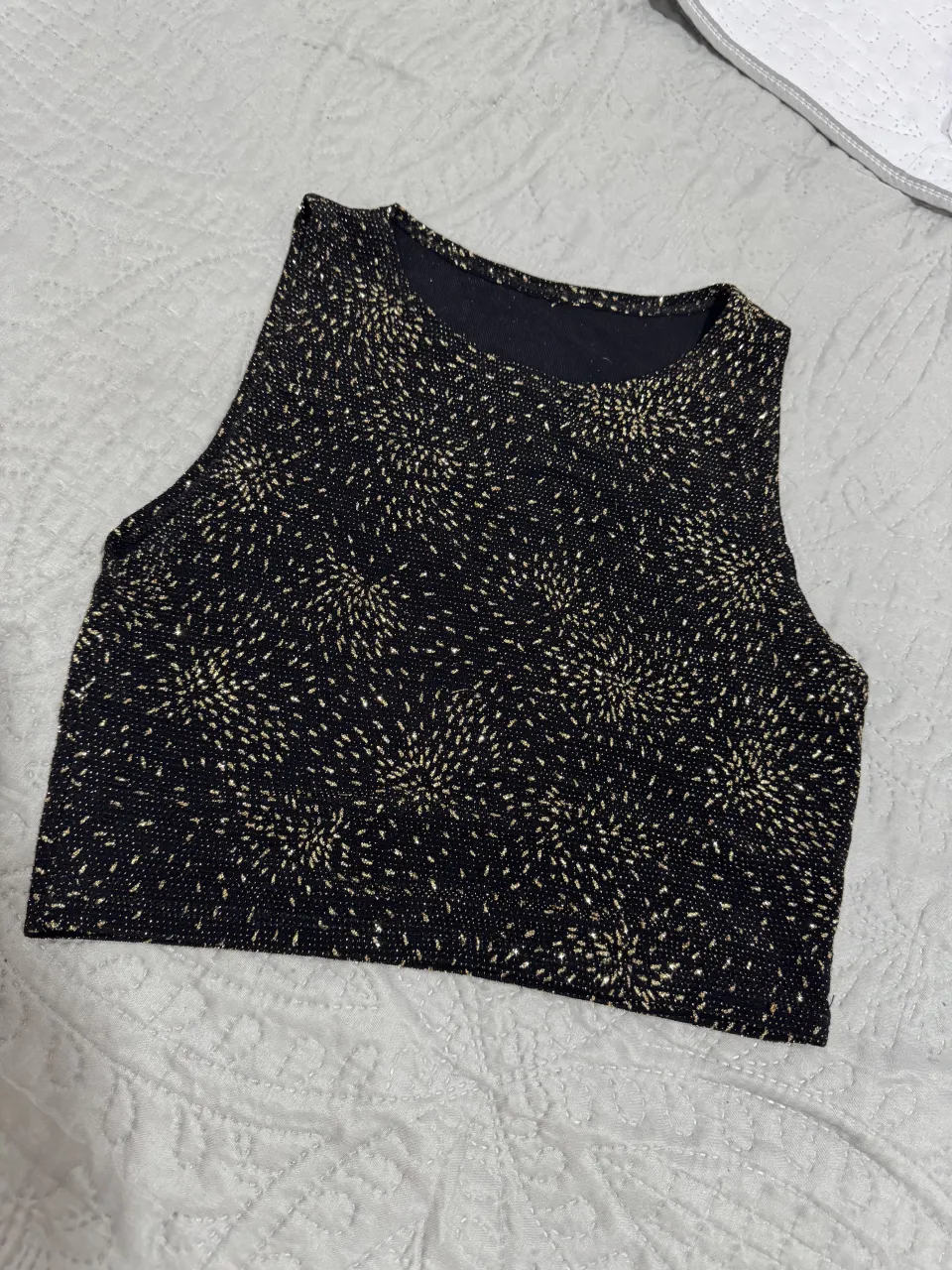 Top negro con estampa de puntos dorados que simulan fuegos artificiales.