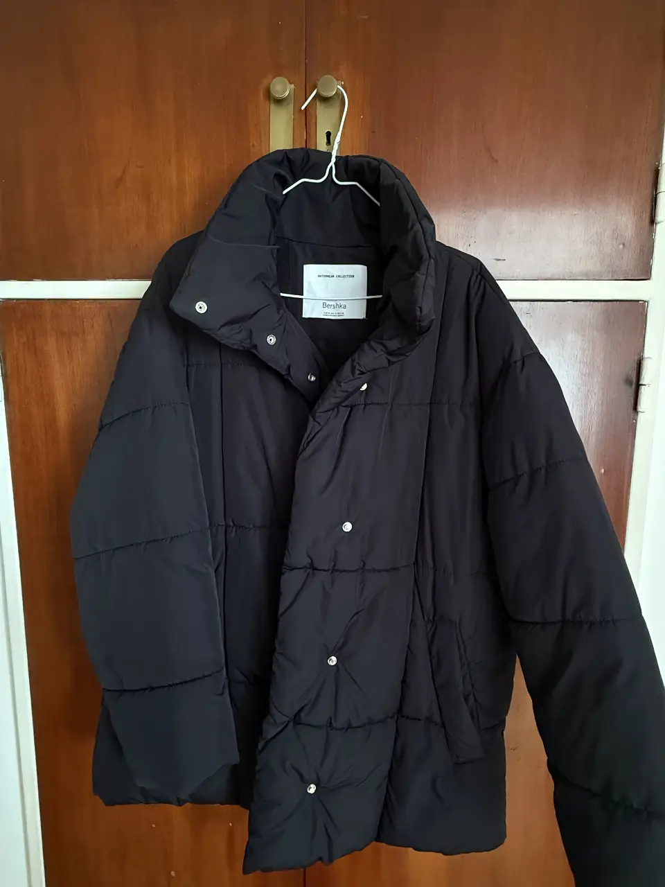 Campera puffer negra oversize de la marca Bershka, ideal para el invierno. Confeccionada con materiales resistentes y diseño acolchado, ofrece abrigo y estilo. Tiene botones y cuello alto.