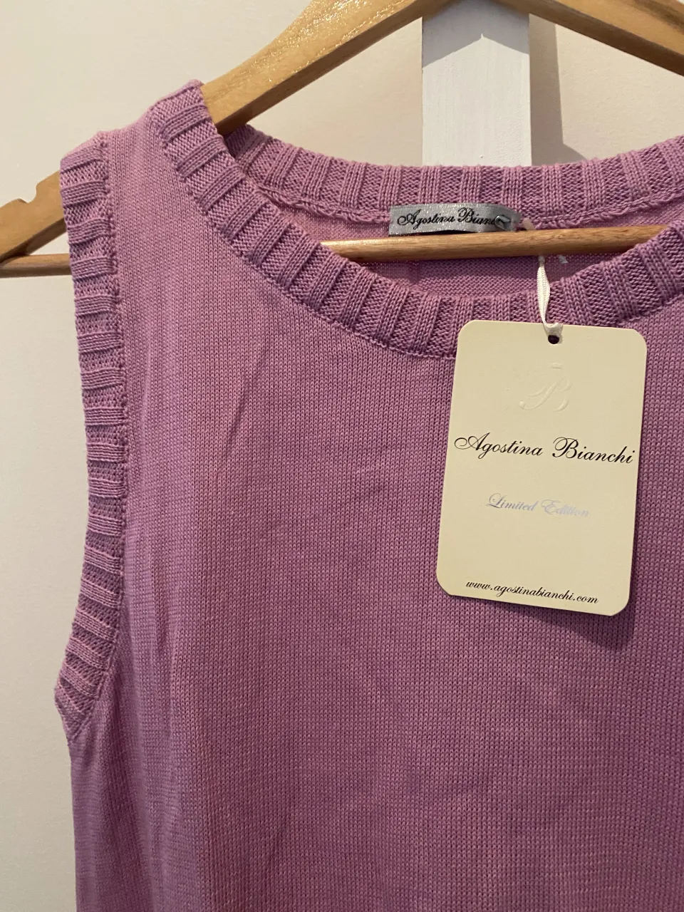 Musculosa de tejido color lila. Posee cuello redondo y terminaciones acanaladas en cuello, sisas y ruedo. El ruedo tiene un detalle de volados.