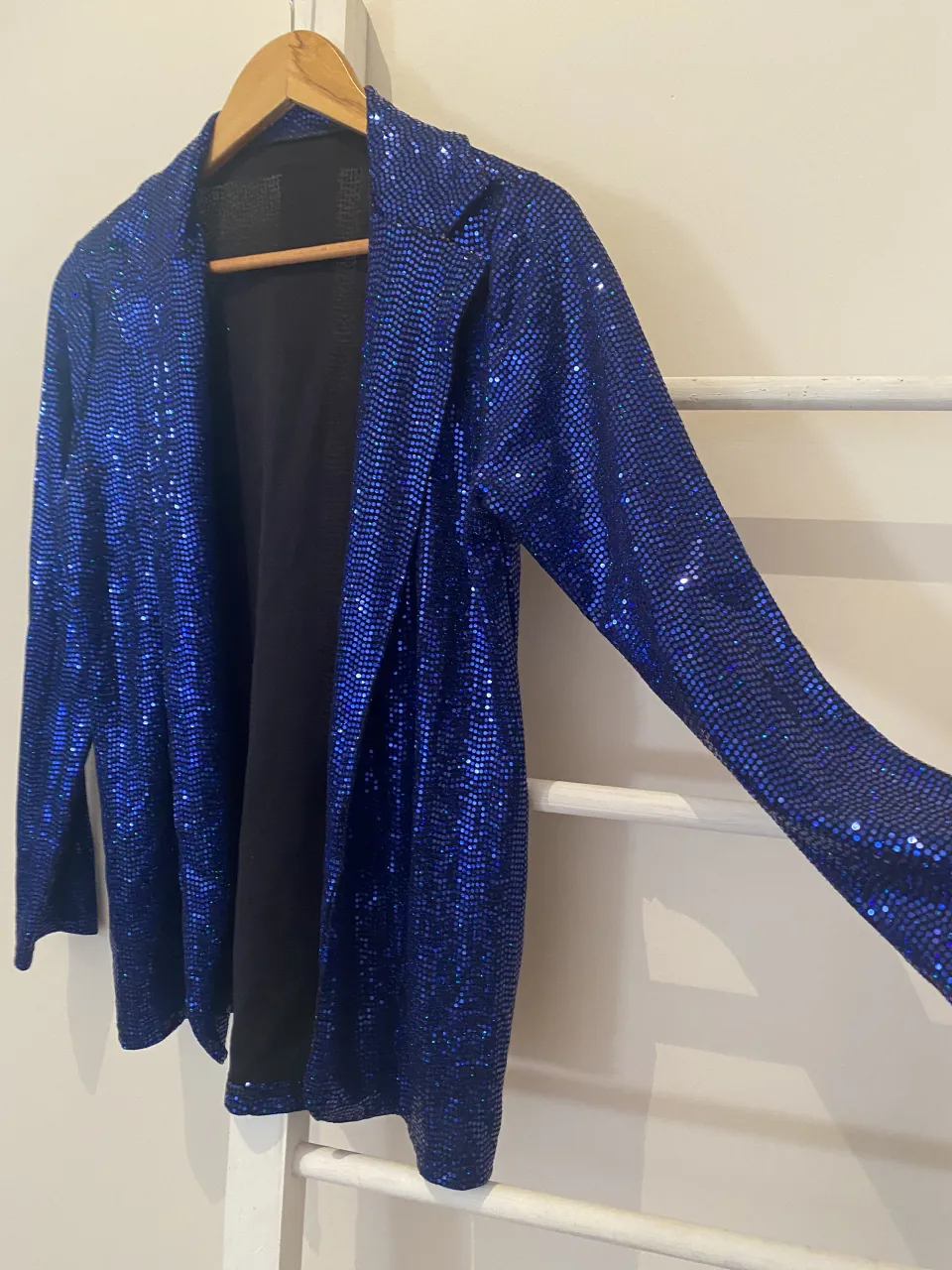 Blazer azul con lentejuelas brillantes, manga larga y cuello solapa. Interior forrado en negro.