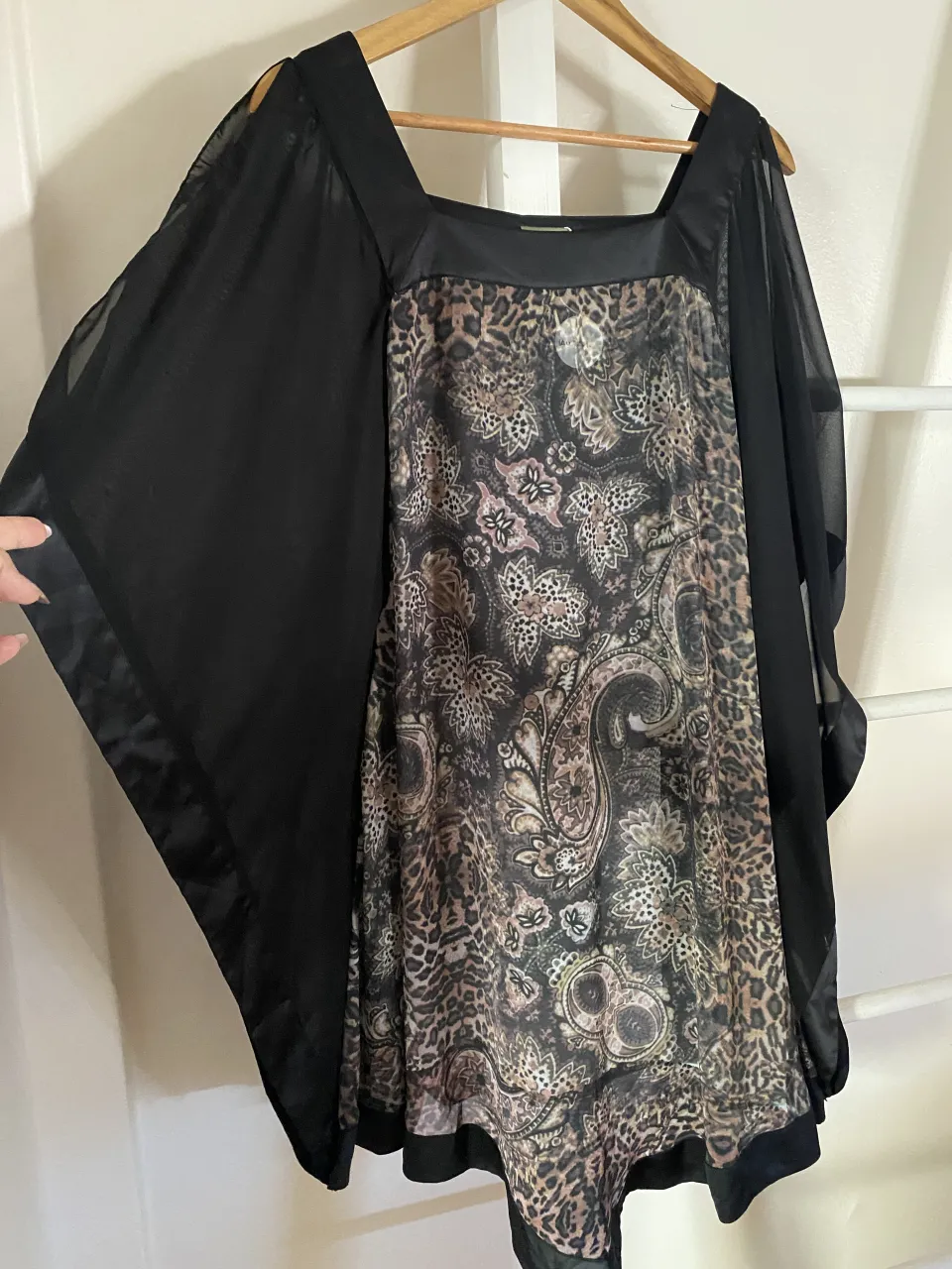 Blusa negra con mangas amplias de gasa y frente estampado con diseño paisley y animal print. Escote cuadrado.