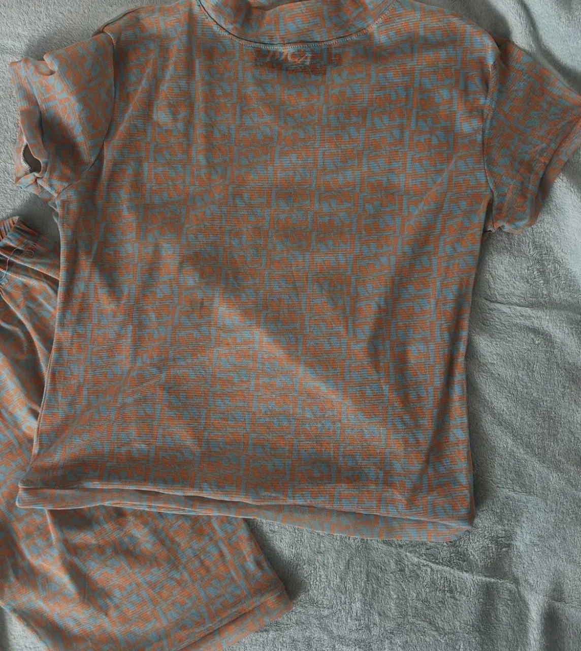 Conjunto de remera y pantalón corto estampado en naranja y celeste. La remera es de cuello alto y manga corta. El pantalón corto es de tiro alto con cintura elástica. DE MICROTUL 