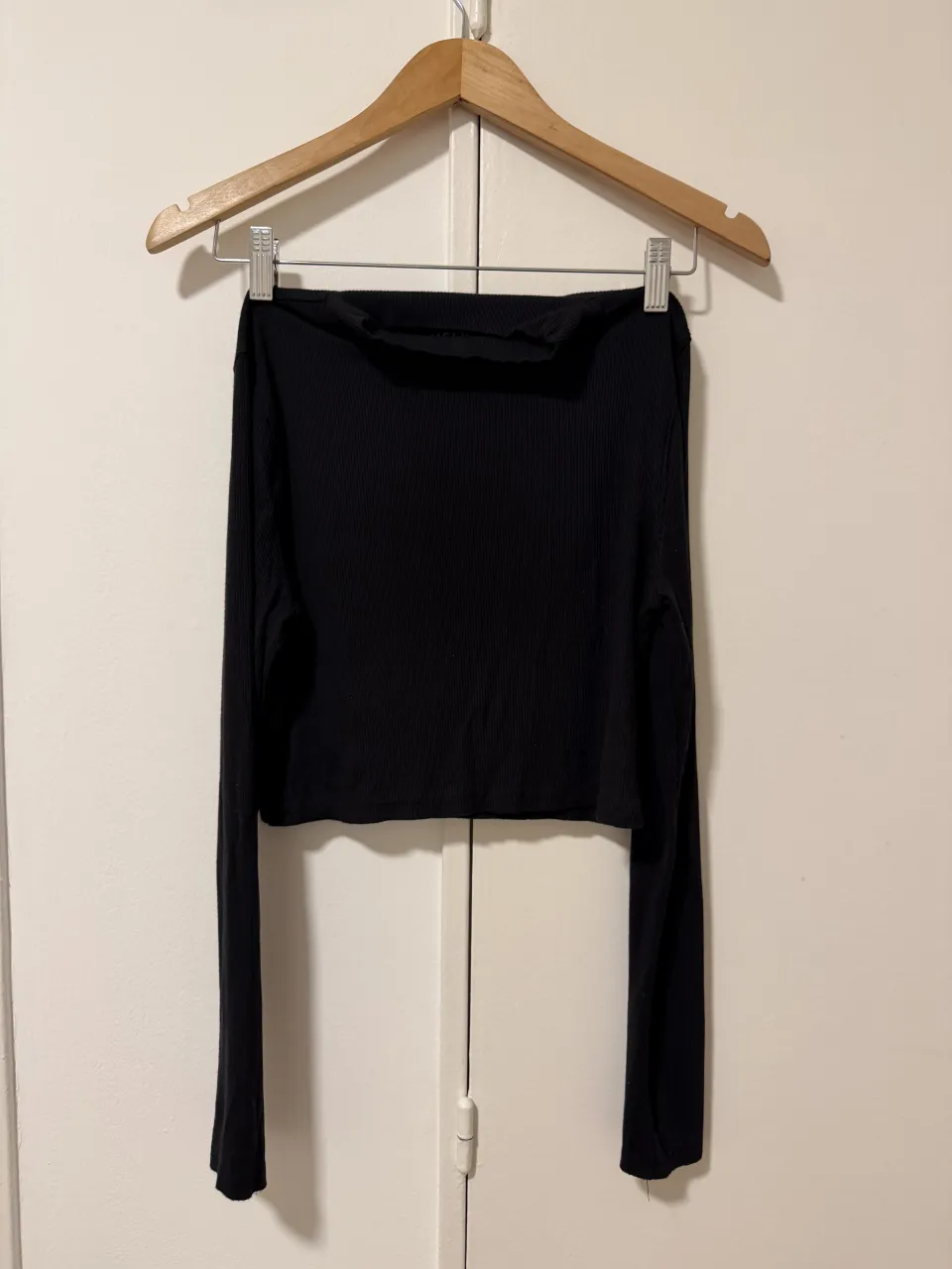 Remera negra de manga larga, escote redondo y corte al cuerpo. Ideal para un look casual y moderno.