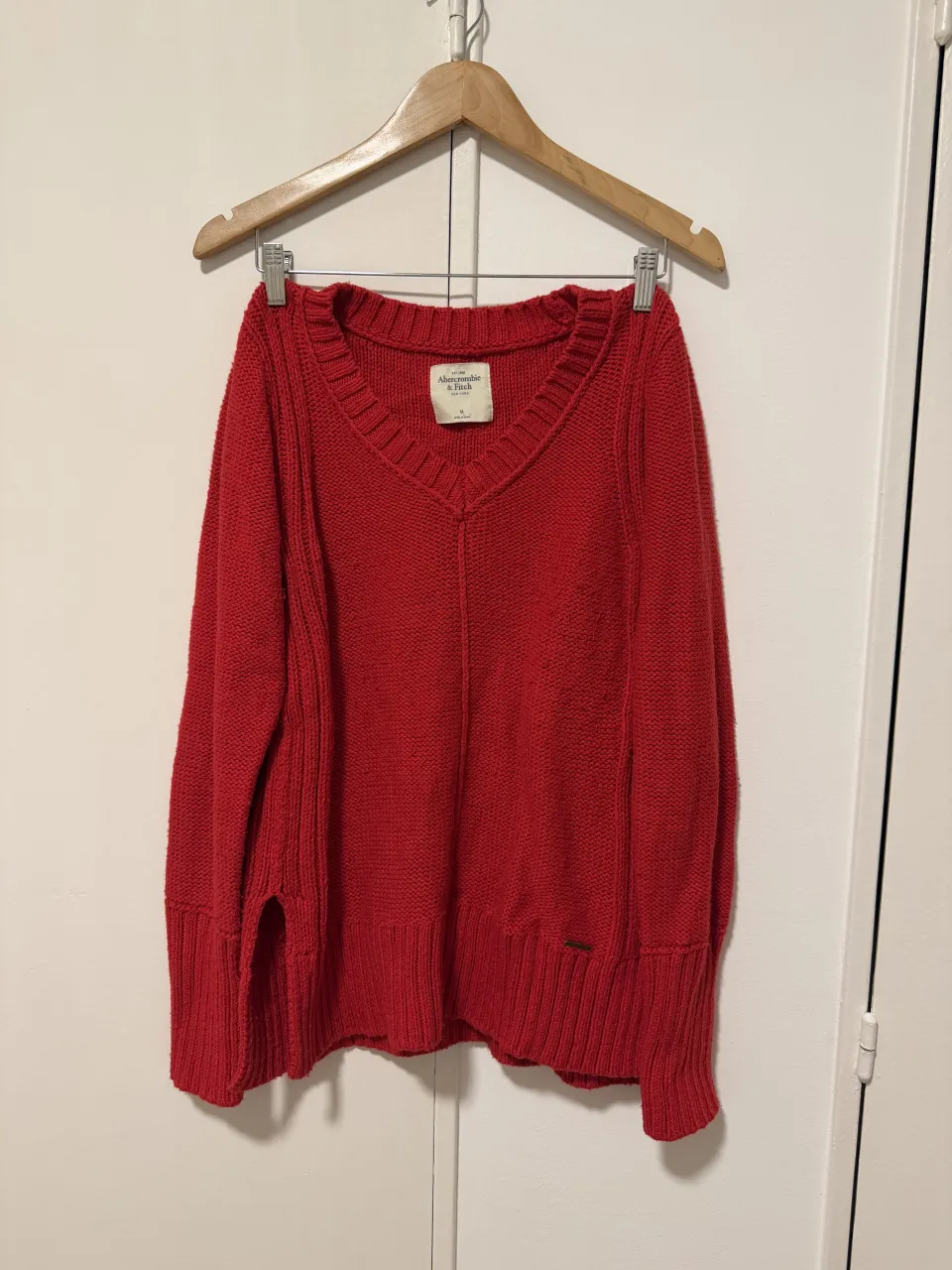 Sweater de lana rojo, escote en V, con puños y cintura tejidos. Ideal para un look casual y cómodo. Marca original
