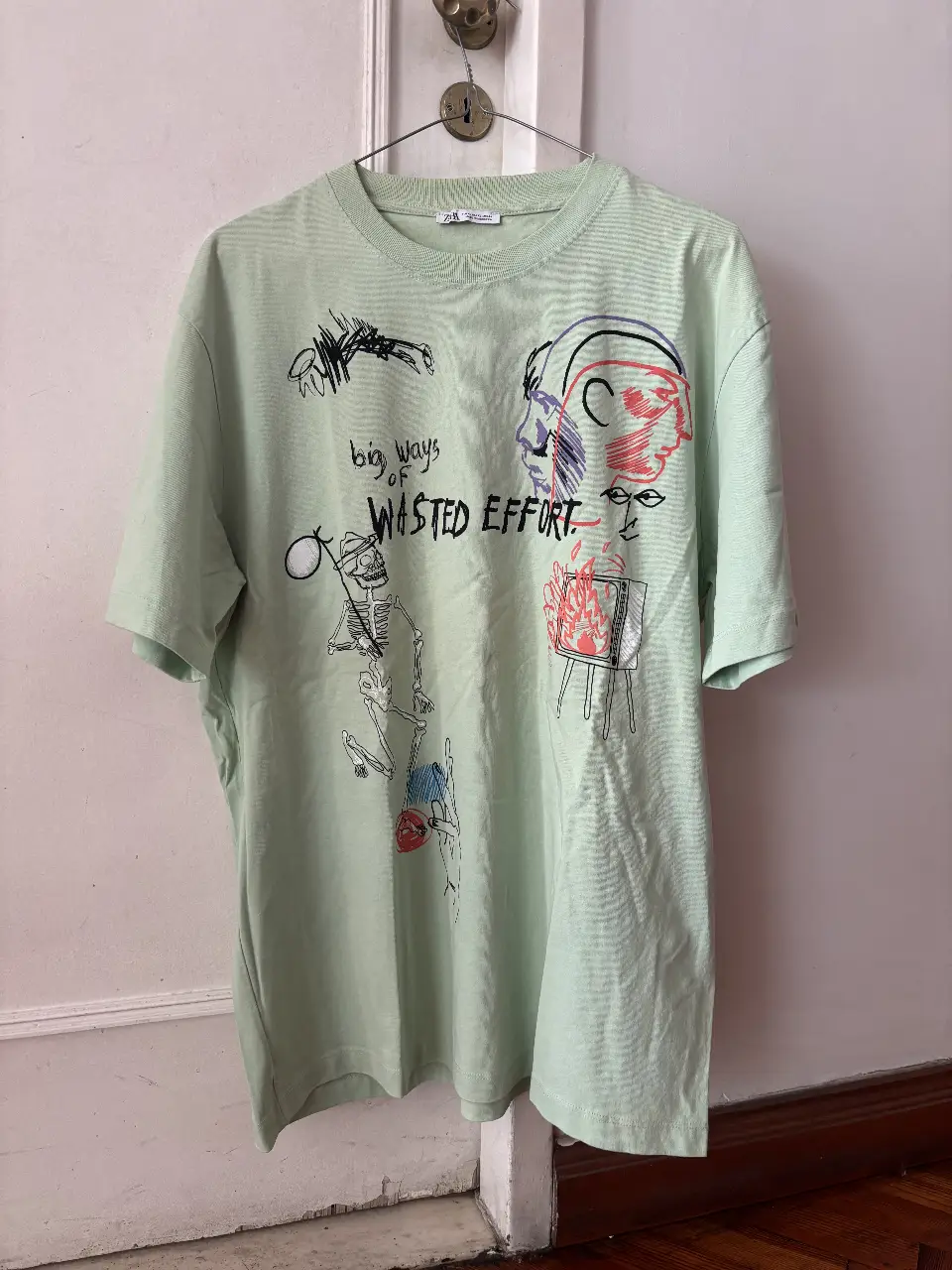 Remera de hombre de color verde claro con estampado artístico en la parte delantera y trasera. Diseño con ilustraciones y frases. Talle XL.