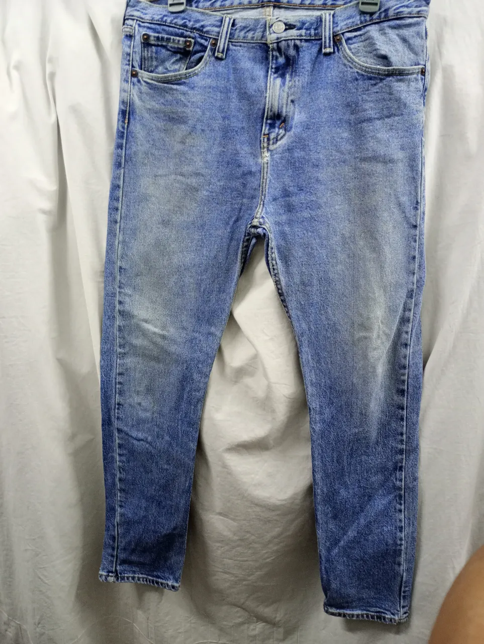 Jeans de algodón de corte clásico, color azul claro con desgaste y detalles de lavado. Presentan bolsillos delanteros y traseros.