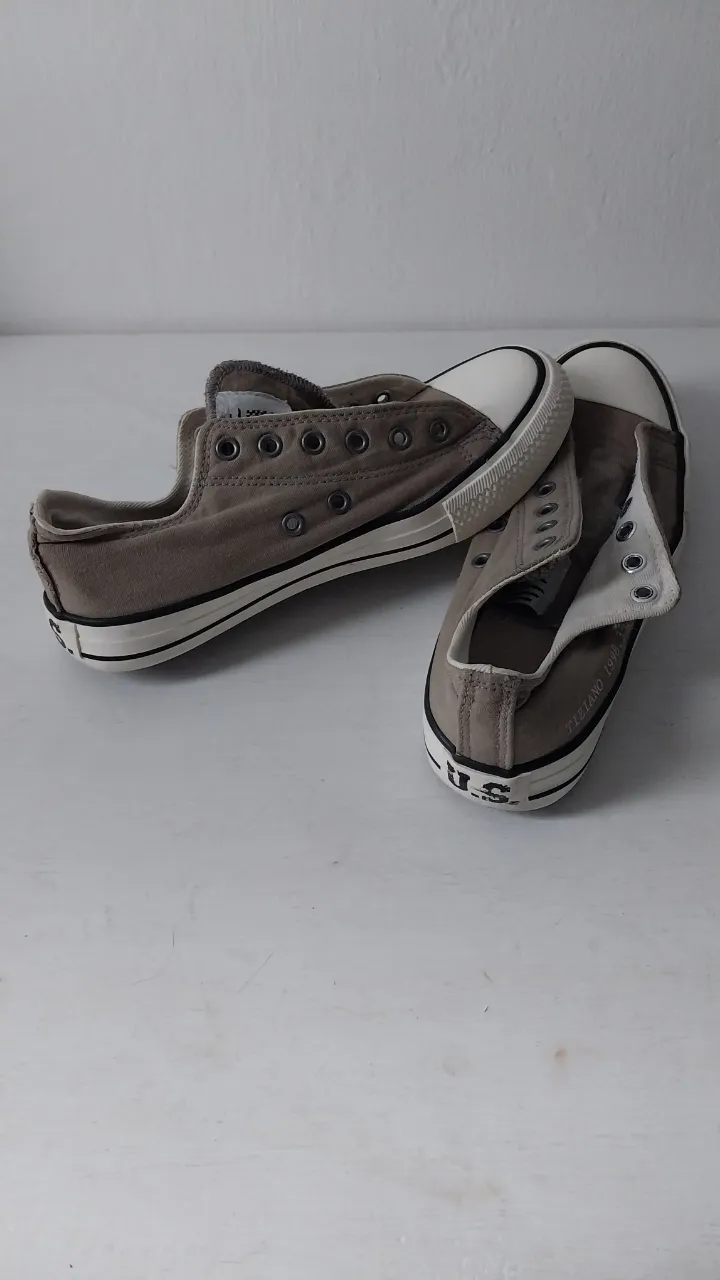 Zapatillas bajas de lona color gris. Tienen sus cordones. Detalle de costuras y puntera reforzada.