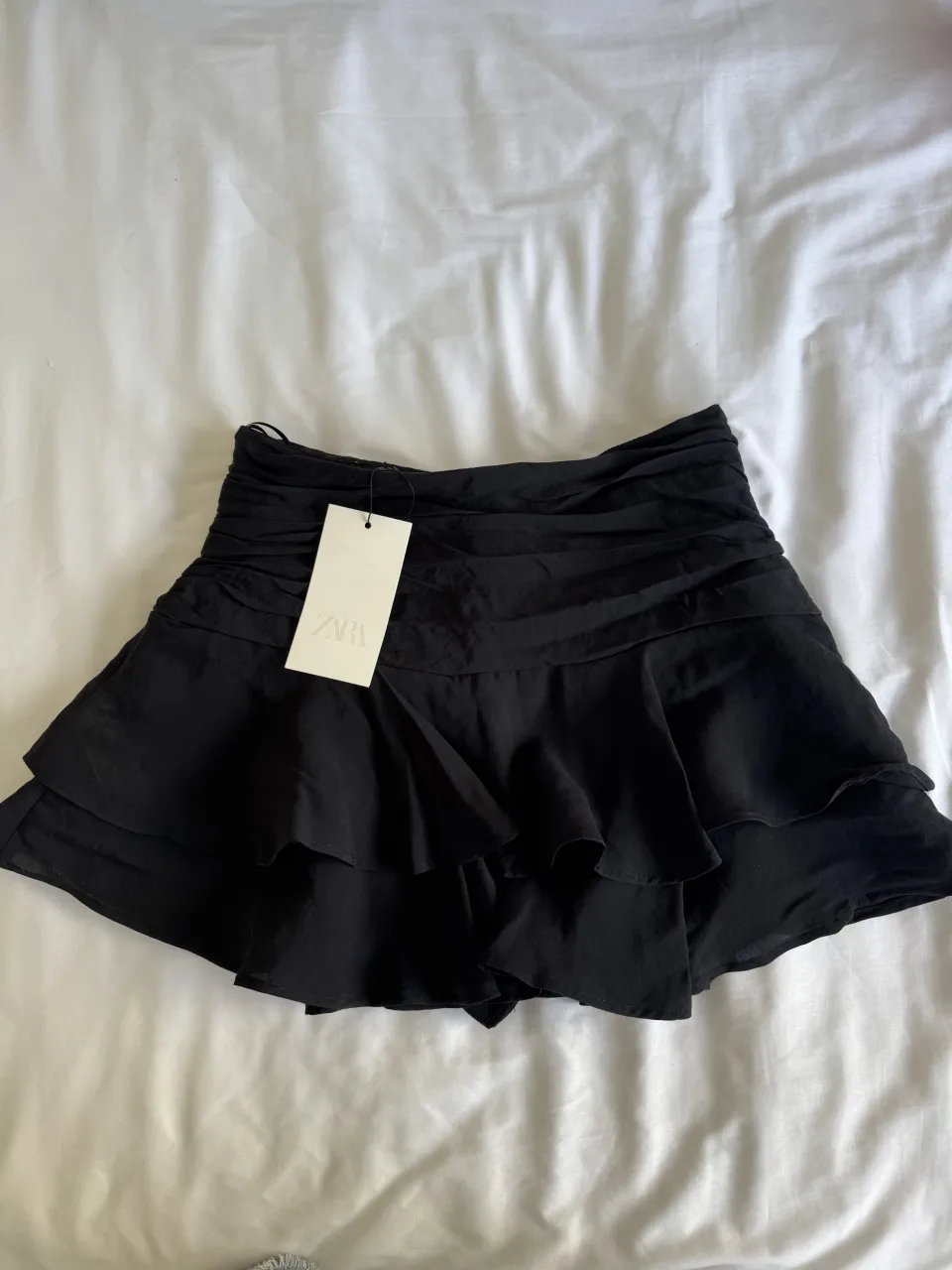 Mini falda negra con volados y fruncido en la cintura. ¡Perfecta para un look canchero y femenino!