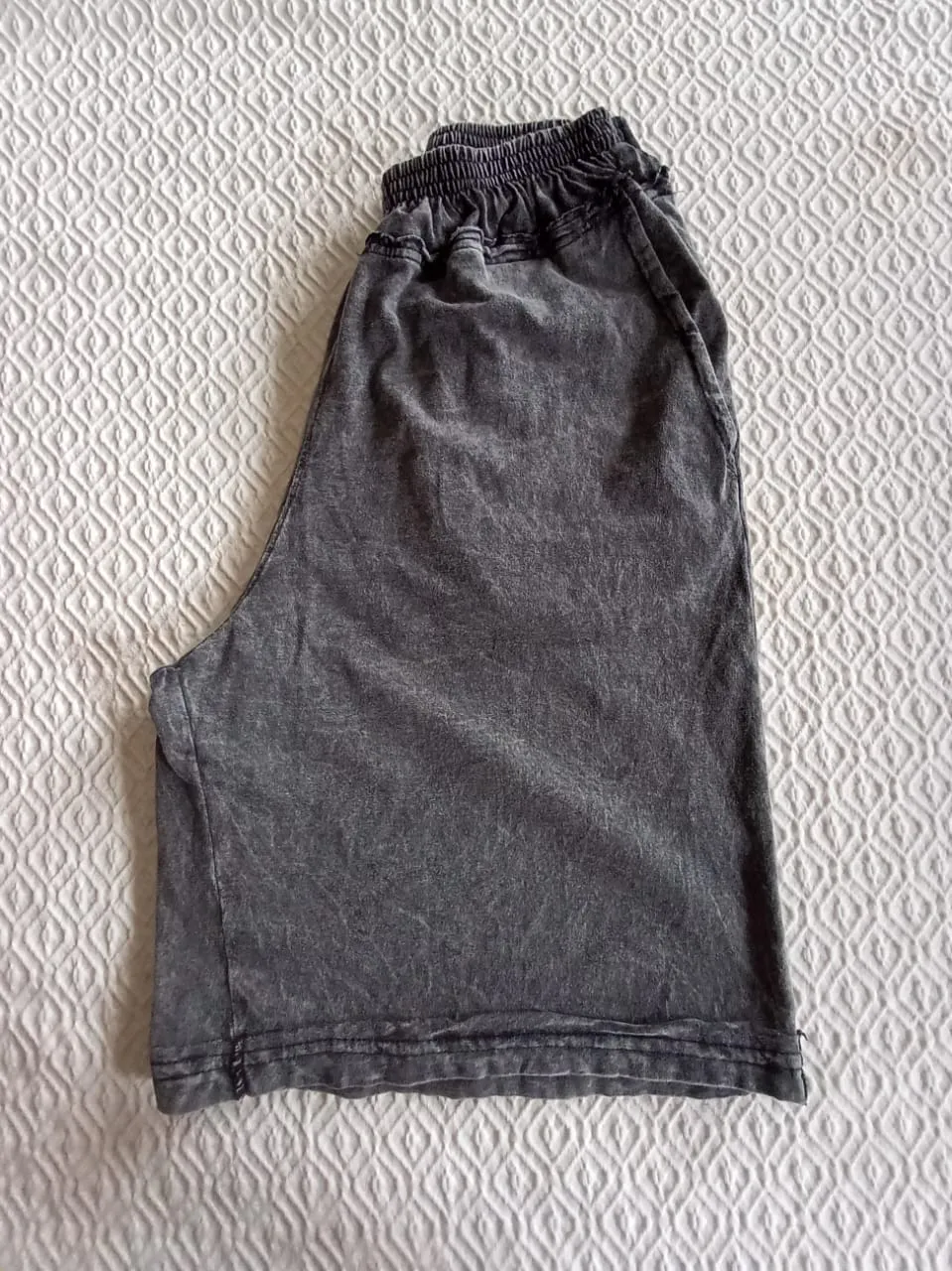 Shorts de algodón gris con efecto desgastado. Cintura elastizada con cordón para un ajuste cómodo. Ideales para el día a día o para estar en casa.