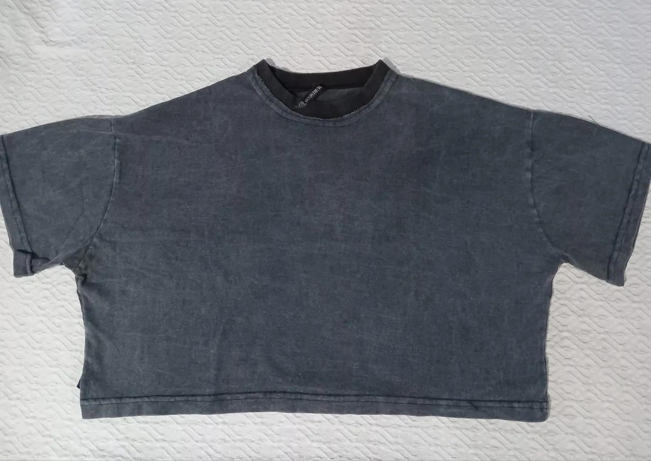 Remera gris oscuro con efecto desgastado, corte crop y cuello redondo. Un básico canchero para looks urbanos.