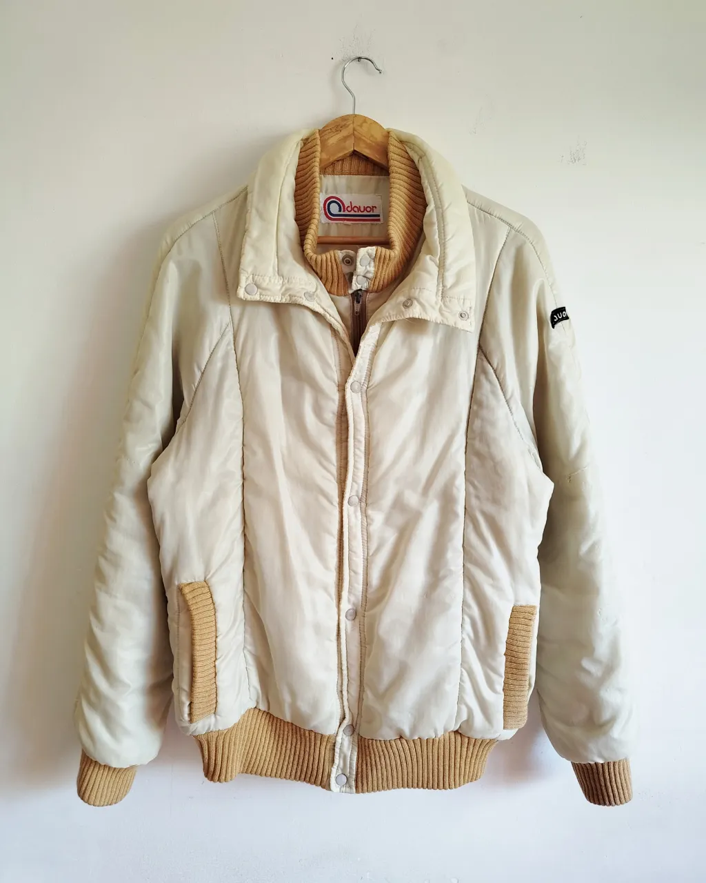 Campera vintage  años 80, de abrigo color crudo con detalles y puños de tejido color ocre. Cierre principal con broches a presión. Cuello alto con tejido.