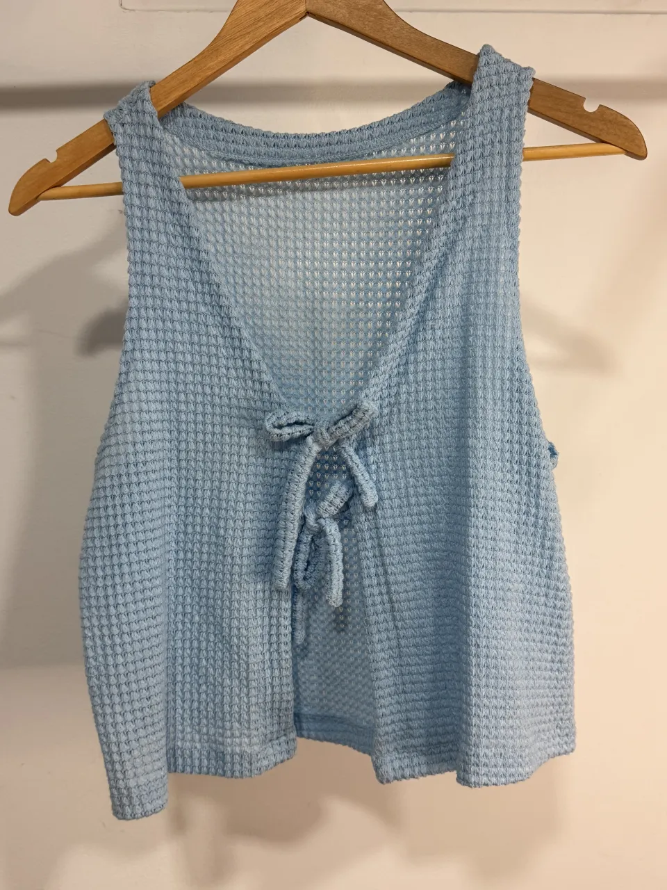 Top tejido de color celeste, con escote en V y detalle de lazo para atar. Ideal para un look casual y fresco.