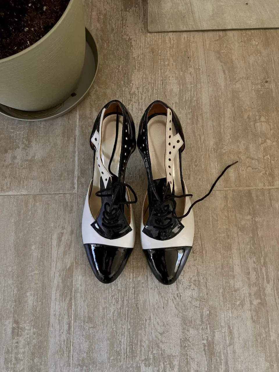Elegantes zapatos de tacón bicolor blanco y negro, con diseño de cordones y detalles de charol. Ideales para eventos formales o para darle un toque sofisticado a cualquier outfit.
