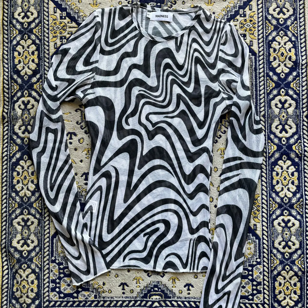 Remera manga larga con estampado de diseño psicodélico en blanco y negro. Ideal para un look moderno y audaz. Perfecta para combinar con jeans o pantalones de cuero.