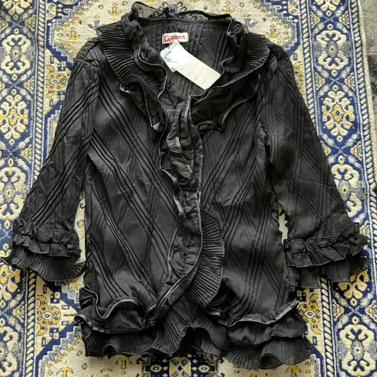 Blusa negra con detalles de volantes y plisados, ideal para un look elegante y sofisticado. Perfecta para ocasiones especiales o para darle un toque chic a tu outfit diario. translucida. nueva con etiqueta