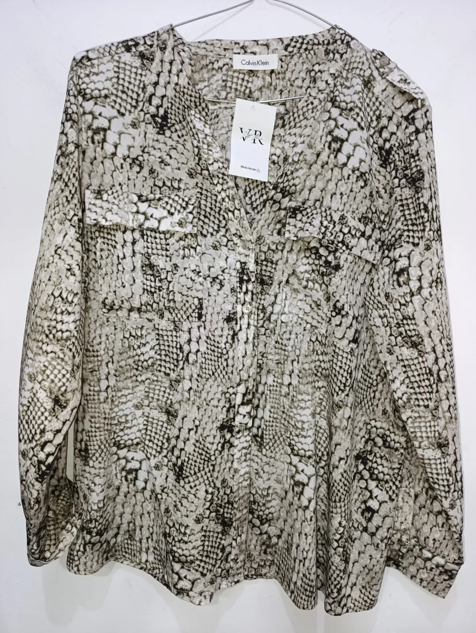 Camisa estampada con cuello escote en V y mangas largas. Posee dos bolsillos en el frente y botones en la parte superior.