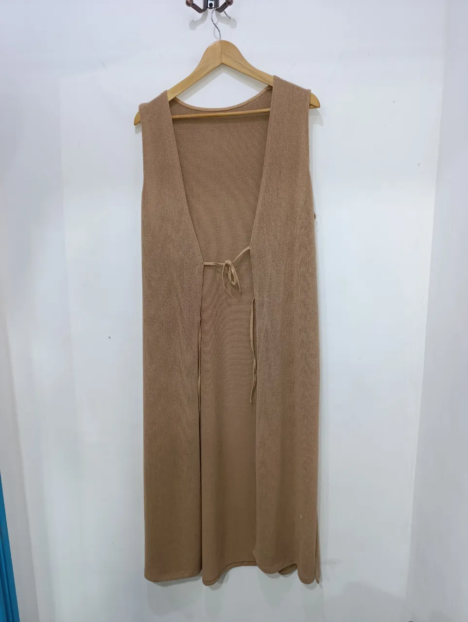 Chaleco largo de tejido abierto, color marrón claro, con lazo para atar en la cintura.