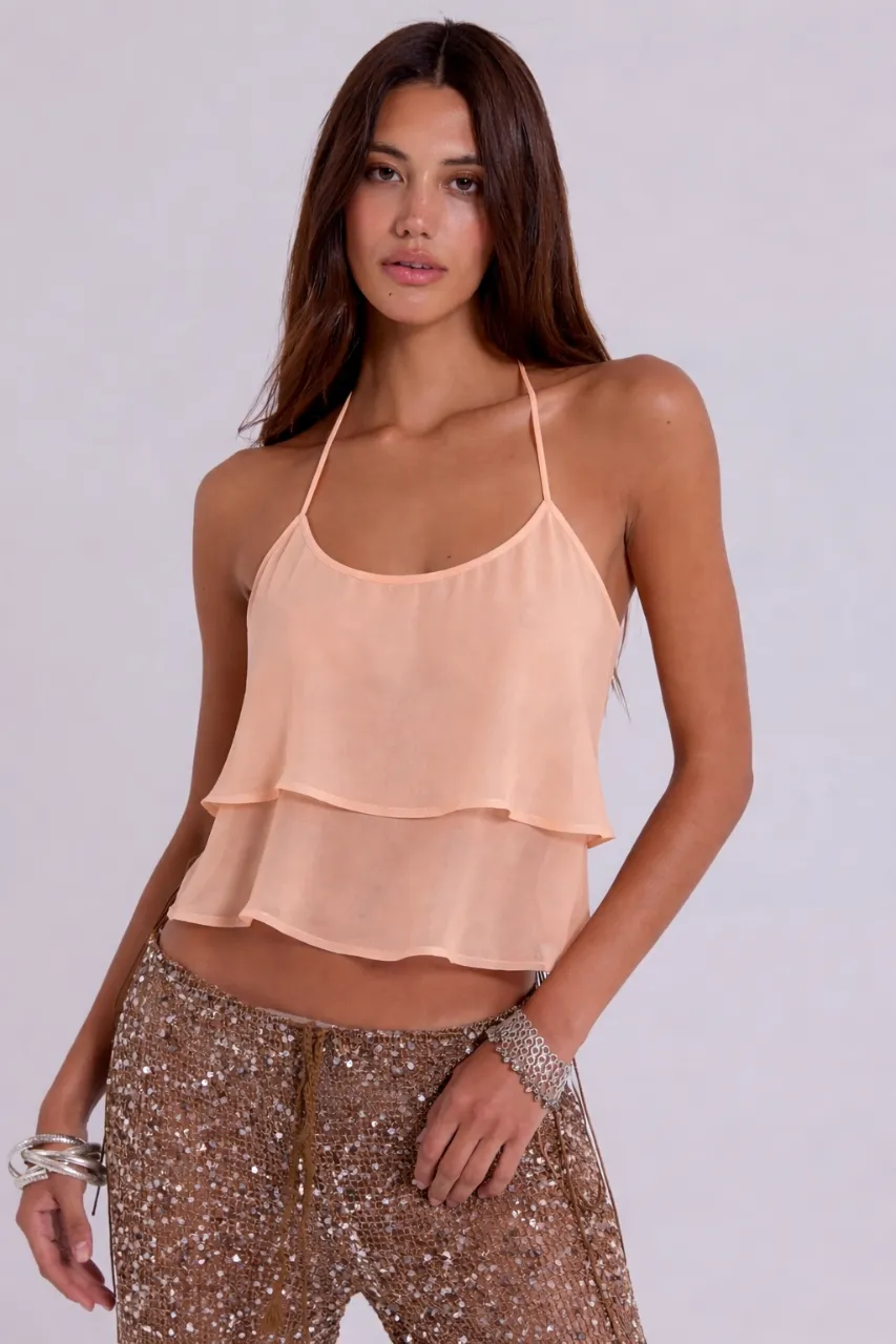 Top de seda color durazno con dos capas superpuestas y tiras finas para atar en el cuello. Pantalón largo de lentejuelas color marrón.