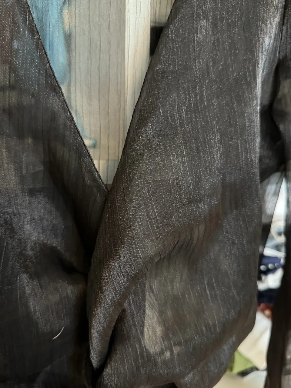 Blusa negra de manga larga con escote en V y detalle de nudo en la parte delantera. Las mangas son amplias y terminan en puño.