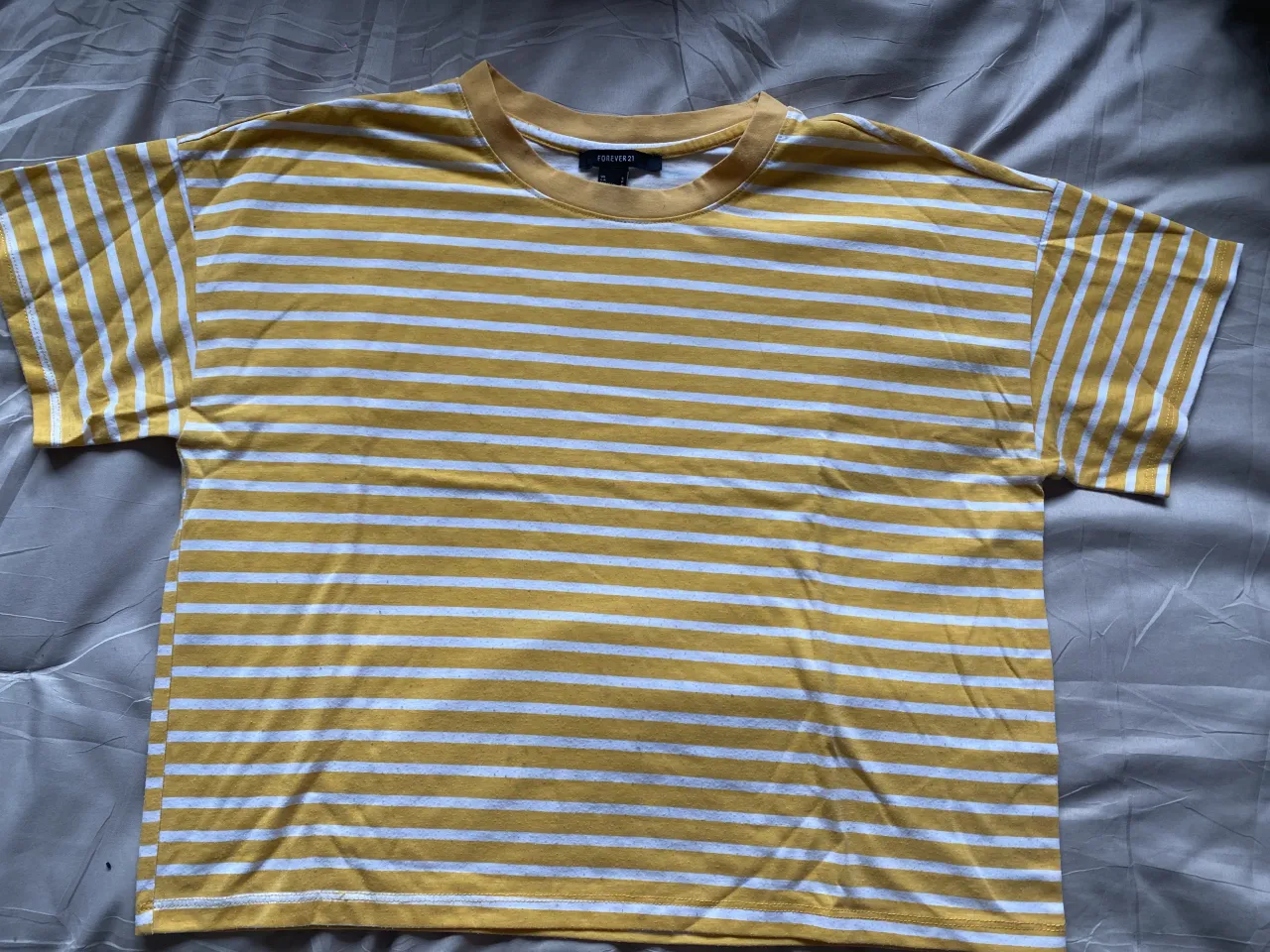 Remera a rayas amarillas y blancas, con cuello redondo y mangas cortas. Un clásico que no puede faltar en tu guardarropa.