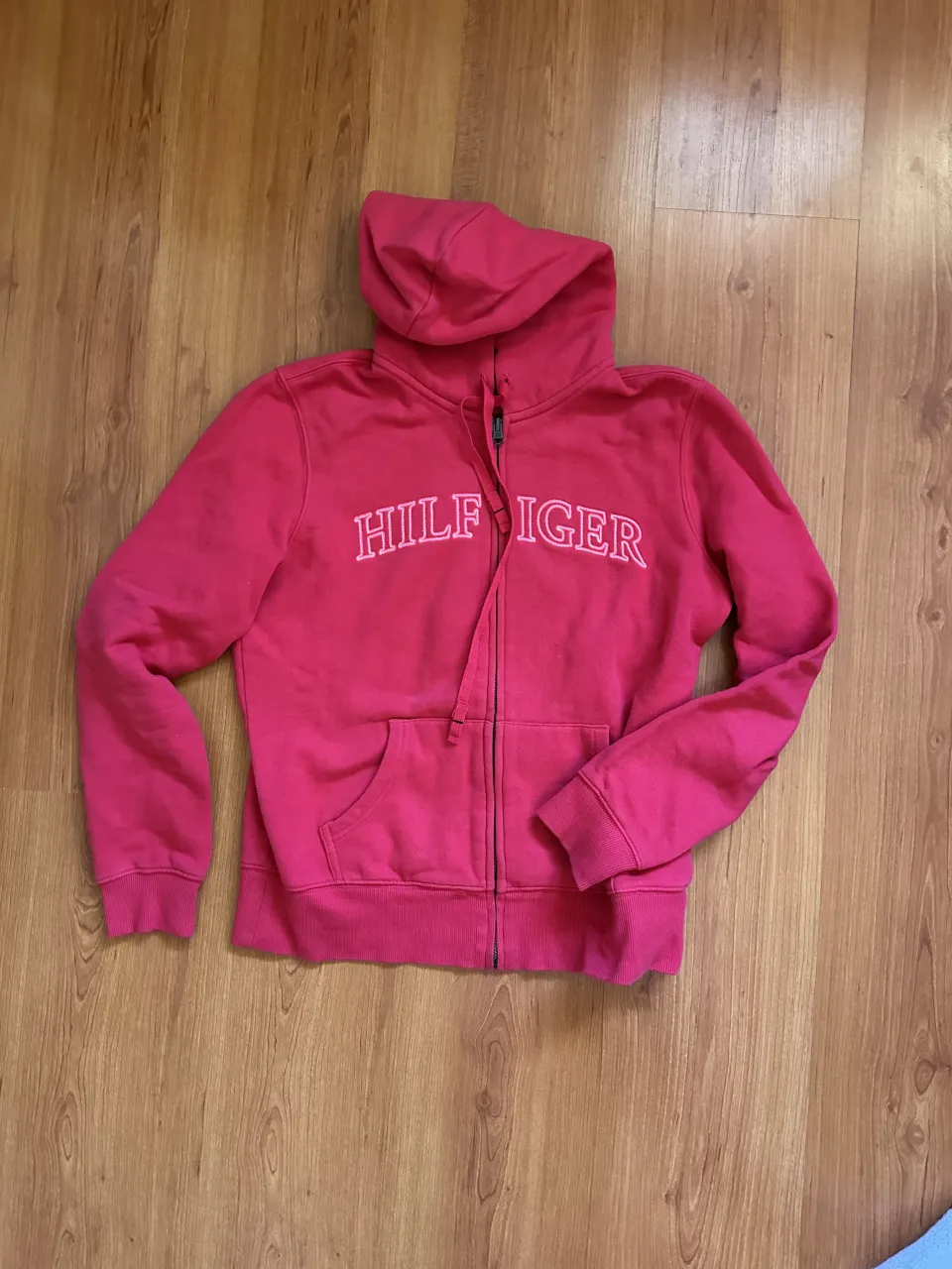 Buzo con capucha y cierre completo. Tiene bolsillos frontales tipo canguro y cordón ajustable en la capucha. El logo de la marca TOMMY HILFIGHERestá bordado en el frente.