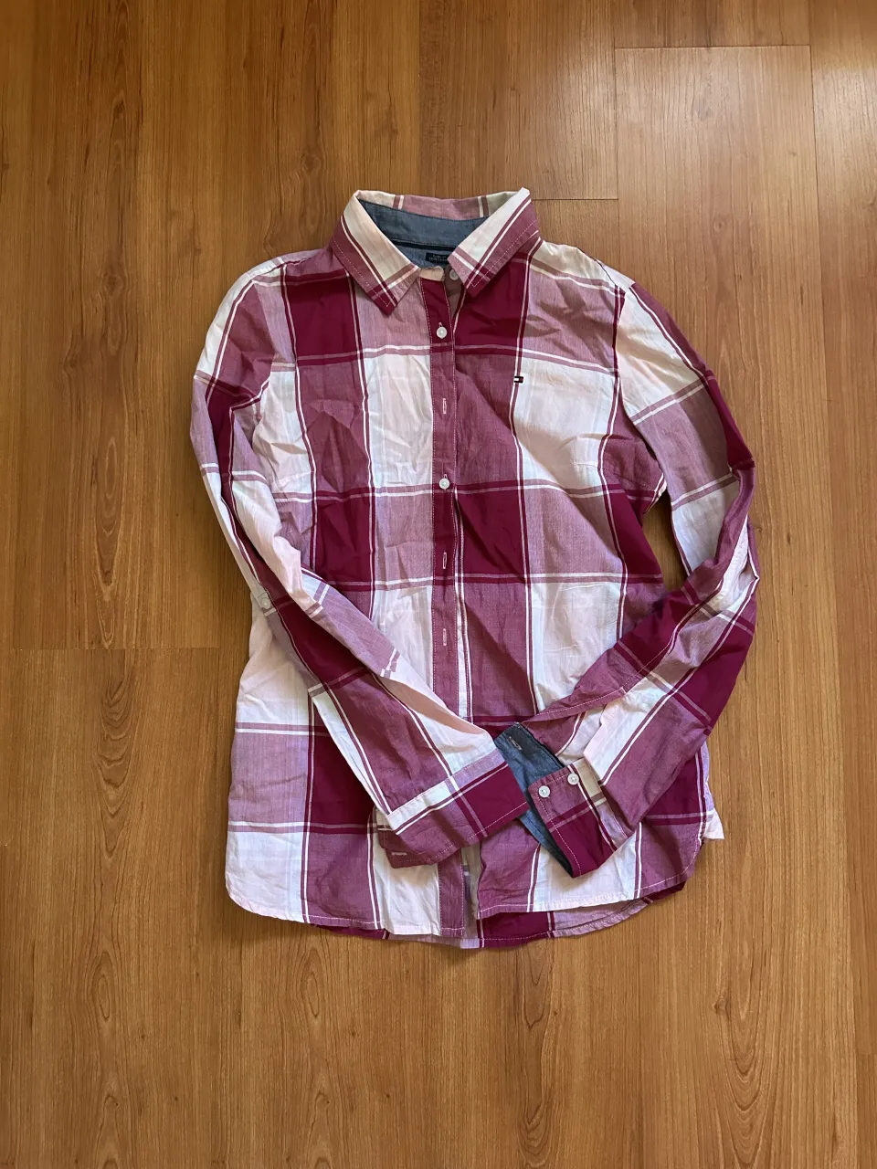 Camisa a cuadros de manga larga con botones al frente. Presenta un logo pequeño en el bolsillo superior izquierdo.