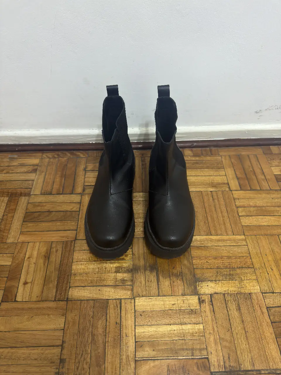 Botines negros de cuero sintético con suela gruesa. Ideales para un look moderno y urbano. Perfectos para combinar con jeans, faldas o vestidos.