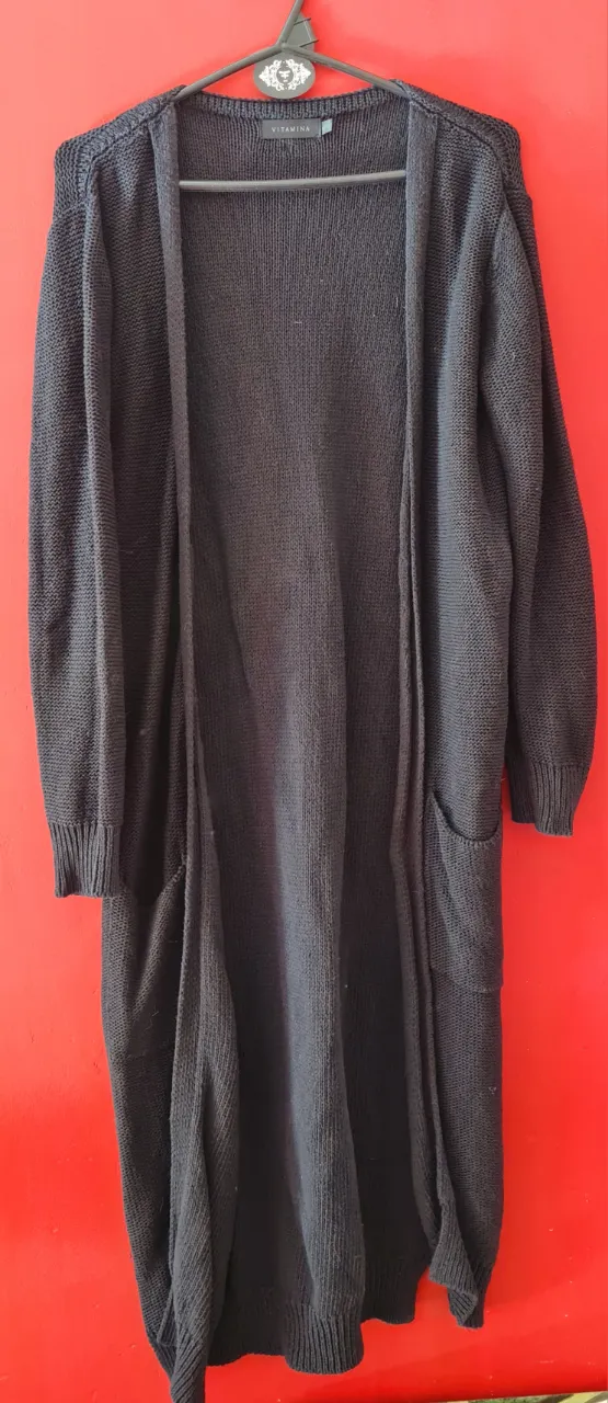Cardigan largo de tejido negro, ideal para un look casual y cómodo. Posee bolsillos frontales y un corte abierto que lo hace muy versátil.