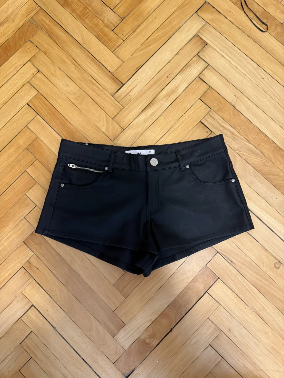Shorts negros con detalles bordados en los bolsillos traseros y un bolsillo con cierre en el frente.