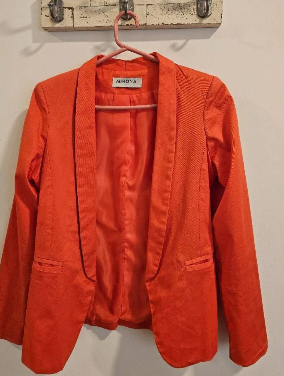 Blazer naranja liso, con solapas y bolsillos frontales.