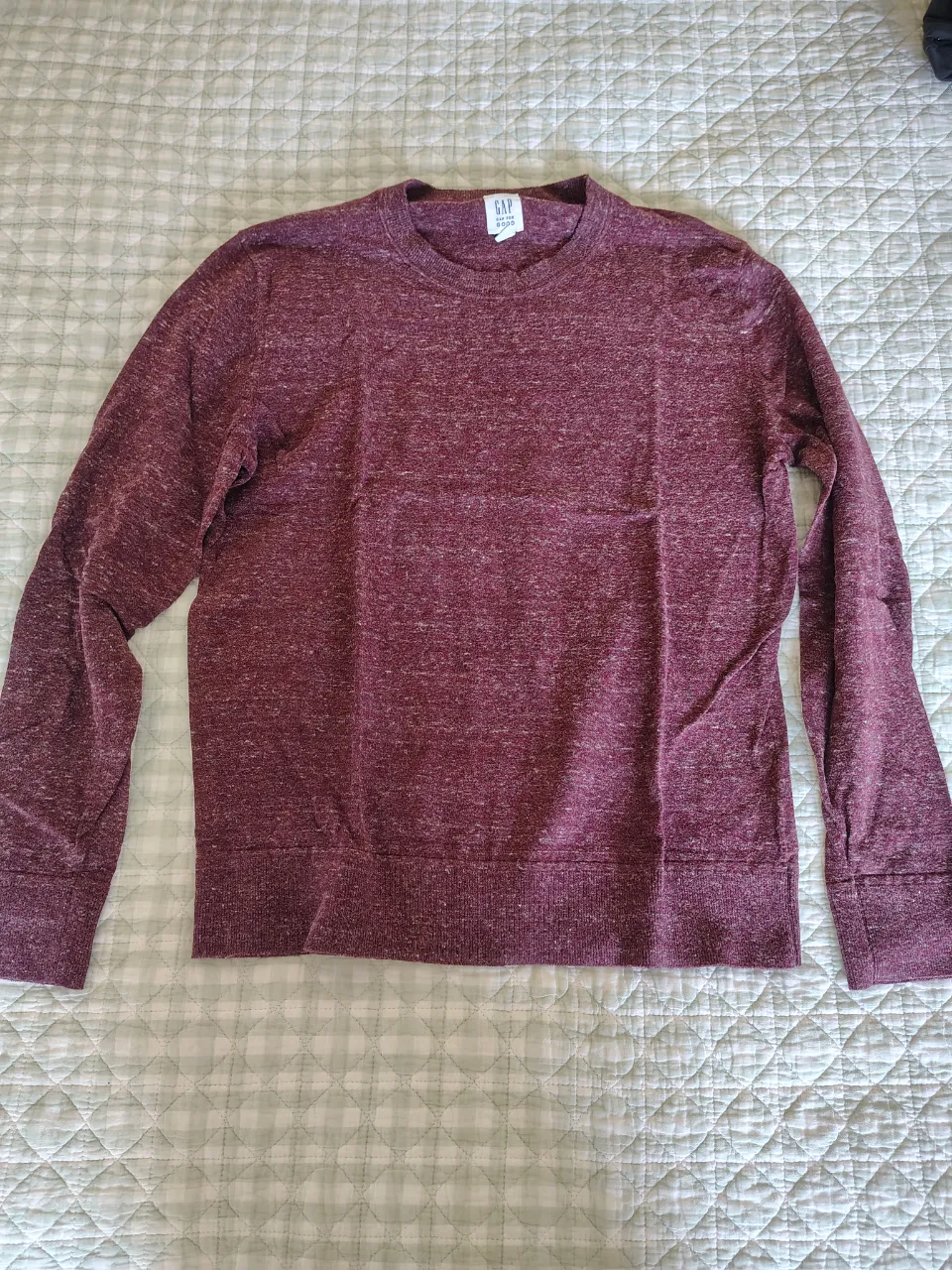 Remera de manga larga de color bordó con detalles jaspeados en blanco. Cuello redondo y puños y cintura de ribb.