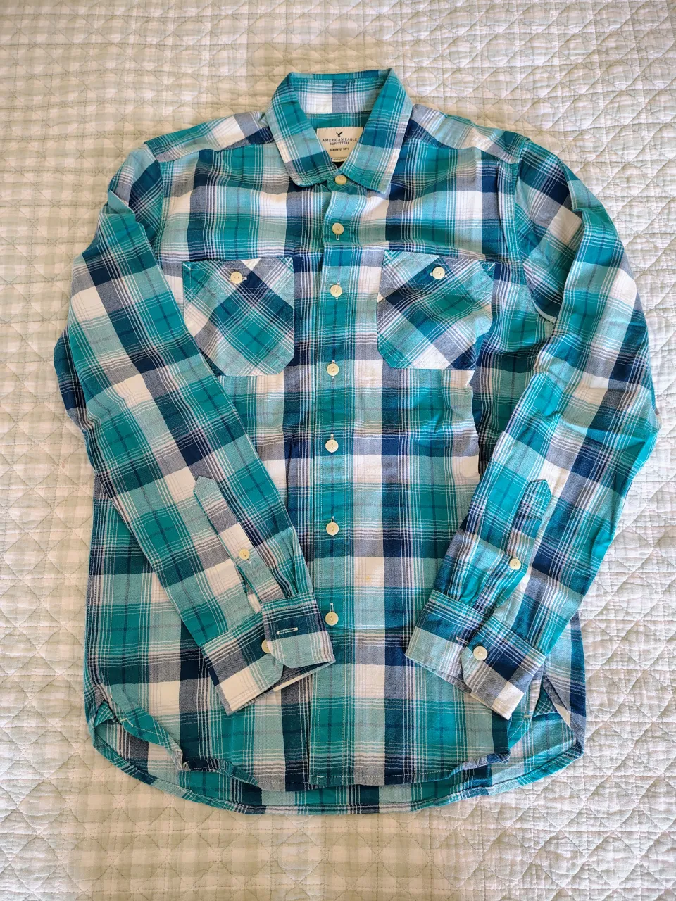 Camisa a cuadros de manga larga con botones al frente y dos bolsillos en el pecho.