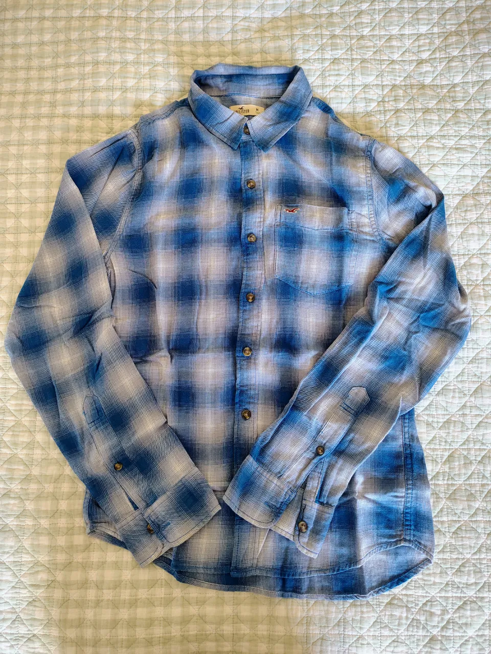 Camisa a cuadros de manga larga con botones al frente. Posee un bolsillo en el pecho.