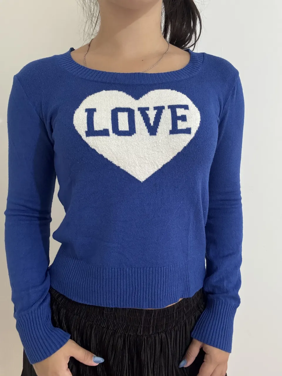 Sweater azul con estampa de corazón blanco y la palabra "LOVE" en el frente. Manga larga y cuello redondo. 