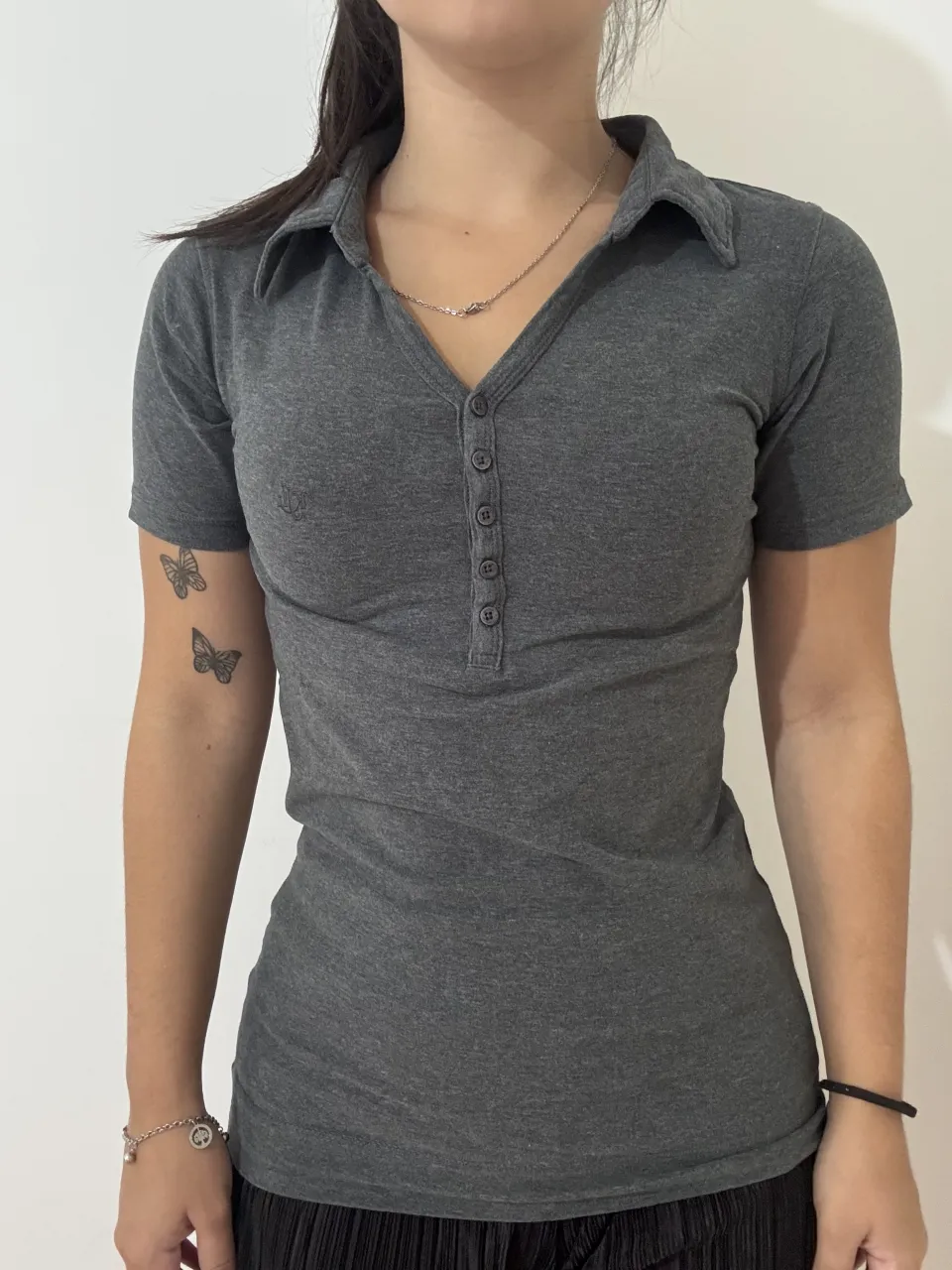 Chomba gris elastizada de manga corta con cuello polo y botones. 