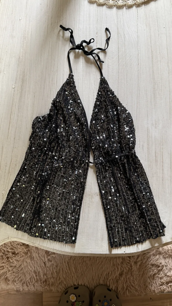 Top negro con lentejuelas plateadas y tiras para atar en el cuello.