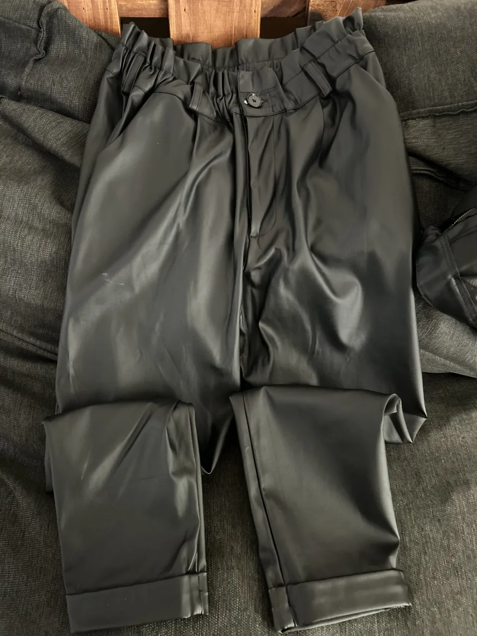 Pantalón de cuero sintético negro, tiro alto con cintura elastizada y fruncida. Diseño moderno y canchero, ideal para looks urbanos y con un toque audaz. Se adapta a diferentes ocasiones, desde salidas casuales hasta eventos más arreglados. Mínimo desgaste en entrepierna 