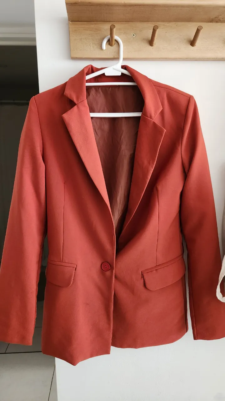 Blazer de color terracota, con un botón al frente y bolsillos con solapa.