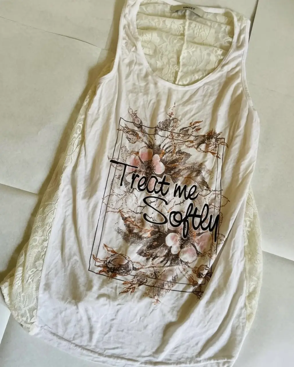 Musculosa blanca con detalle de encaje y estampado "Treat me Softly". Ideal para un look casual y fresco.