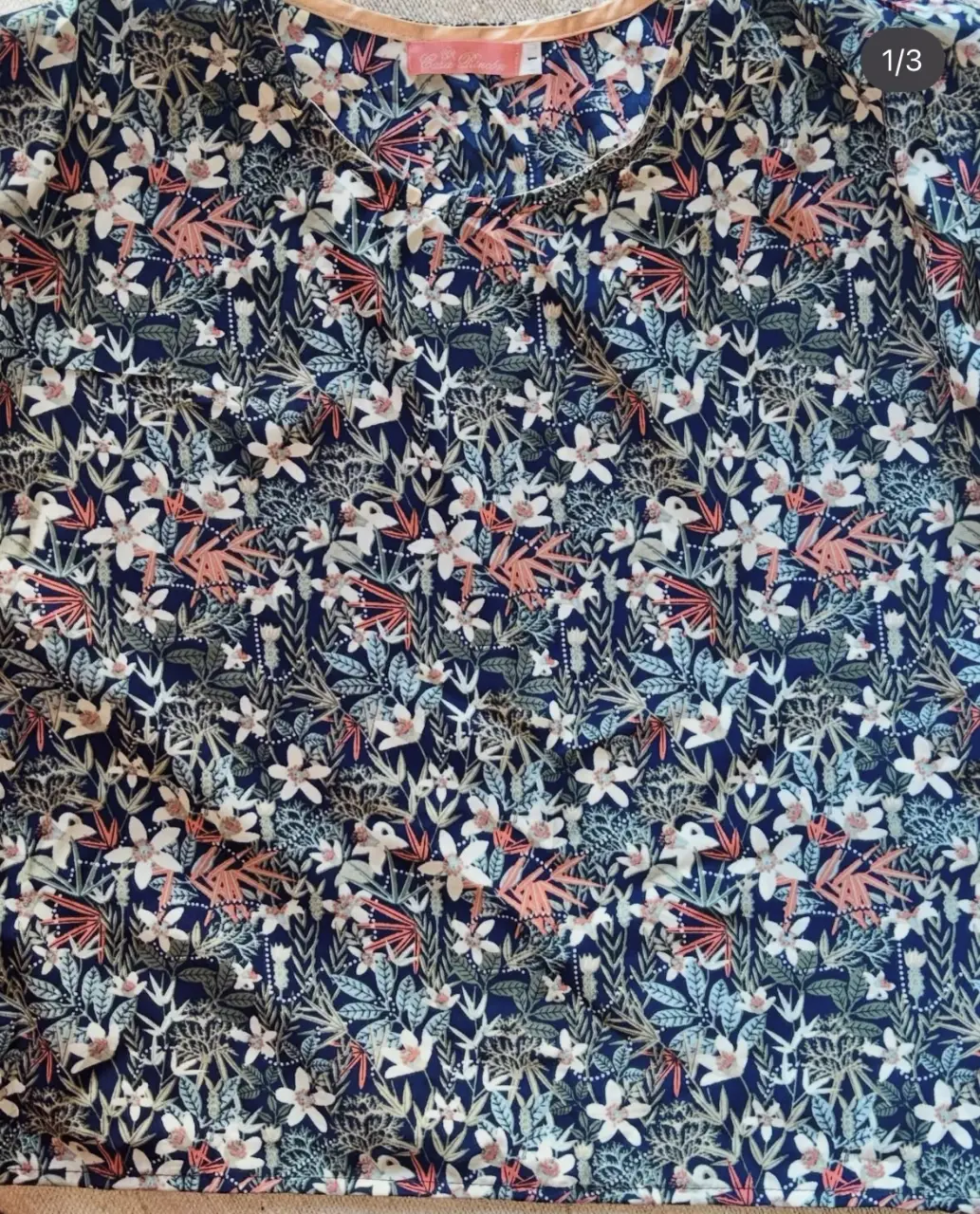 Blusa de mujer con estampado floral en tonos azul marino, blanco y detalles en rosa. Cuello redondo y manga corta. Ideal para un look casual y fresco.