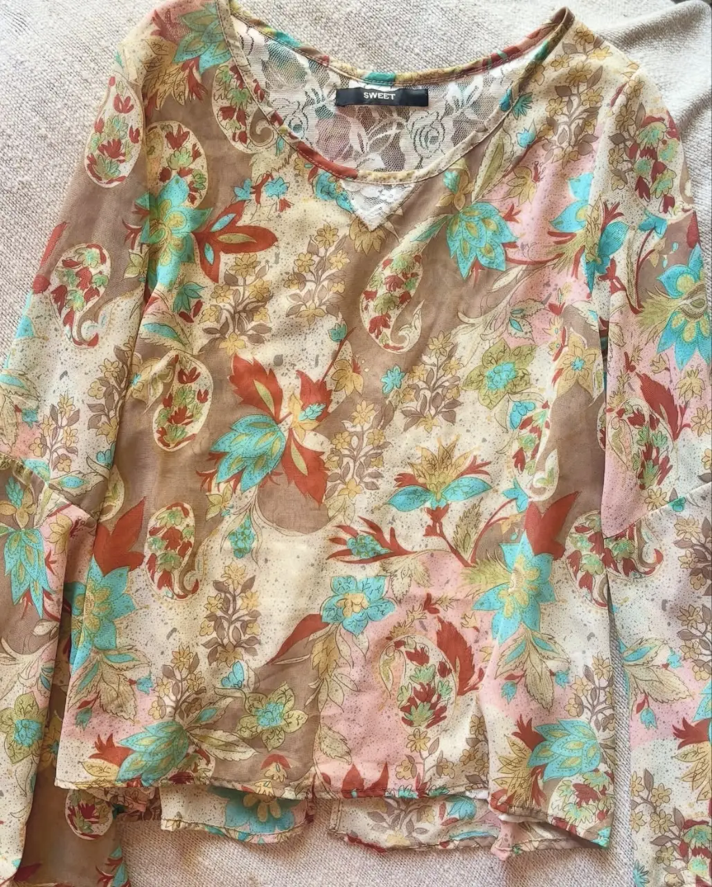 Blusa de mujer con estampado floral en tonos marrones, rosas y celestes. Detalles de encaje en el escote y la espalda. Ideal para un look bohemio y casual.